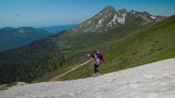 Женщина-альпинистка скользит по снежному склону горы — стоковое видео