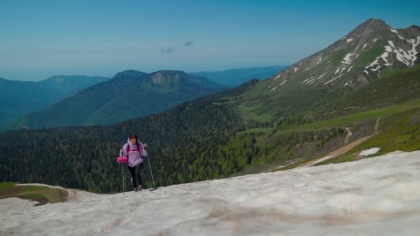 Дівчина робить зусилля, щоб піднятися на сніговий гірський схил — стокове відео