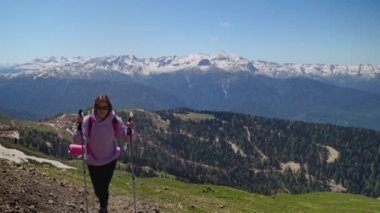 Dağlarda turistik bir gezi, genç bir kadın zirveye tırmanıyor.