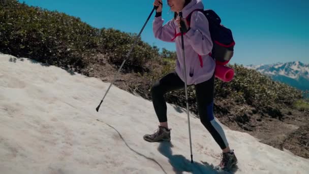 Lány túrázó figyelembe kihívás, hogy túljusson havas lejtőn, és eléri a dombtetőn — Stock videók