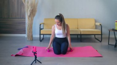 Dambıllı ev eğitimi, kadın ağırlık kaldırıyor ve akıllı telefondan video dersleri alıyor