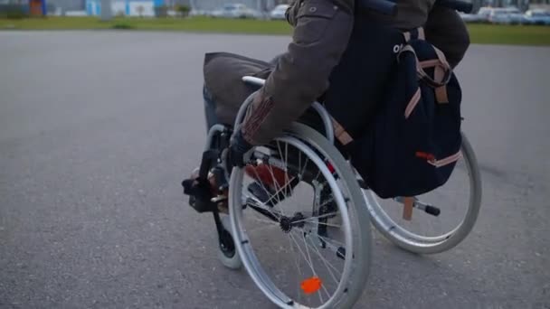 Samostatně zdravotně postižený muž na invalidním vozíku se pohybuje samostatně na městské ulici, zadní pohled — Stock video