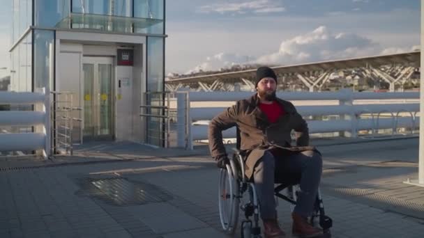 Mężczyzna z niepełnosprawnością fizyczną i paraplegia porusza się na wózku inwalidzkim w mieście — Wideo stockowe