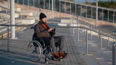 Şehir merdiveninde telefonu olan engelli bir adam.