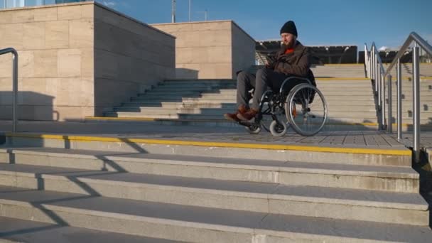 신체 하반신 마비가 있는 남자 가 도시에서 휠체어에 앉아 스마트폰으로 문자 메시지를 보내고 있습니다. — 비디오