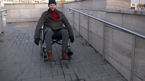 Vrolijke gehandicapte man beweegt zich naar beneden rolstoelhelling — Stockvideo