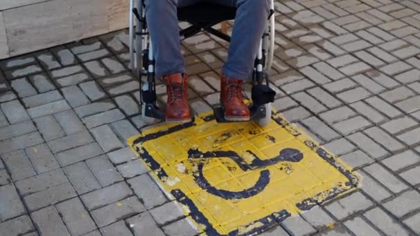 Símbolo amarillo de discapacidad en el suelo de baldosas de la calle y el hombre en silla de ruedas — Vídeo de stock