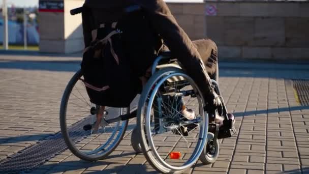 Hombre en silla de ruedas manual se está moviendo en la calle en la ciudad moderna, equipo para personas con discapacidad — Vídeo de stock