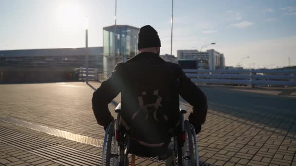 Deficiente homem em cadeira de rodas na cidade, usando transporte manual inválido para se deslocar — Vídeo de Stock