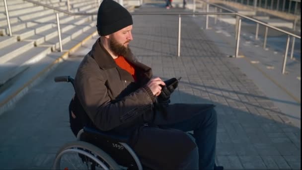 Homme handicapé en fauteuil roulant attend l'aide devant l'escalier en ville, l'envoi de message dans le smartphone — Video