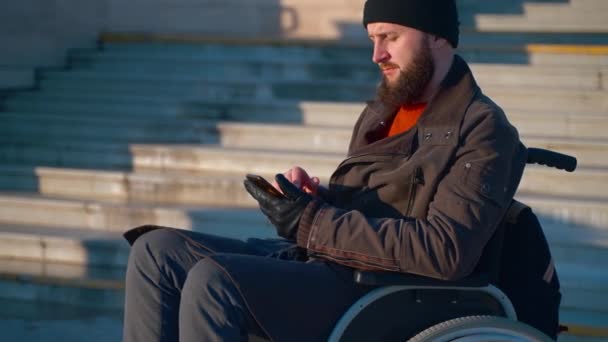 Omul legat de scaunul cu rotile vorbește cu smartphone-ul în aer liber din oraș — Videoclip de stoc
