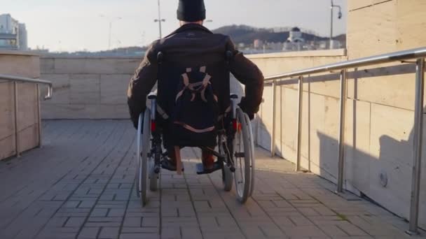 Vuxen man i rullstol använder handikappramp i modern stad för att flytta — Stockvideo