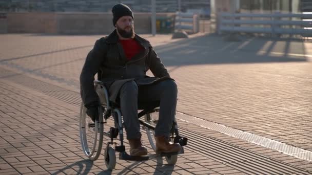 젊은 남자는 신체 장애 인을 가두에서 움직 이 기위해 수동 휠체어를 사용하고 있다 — 비디오