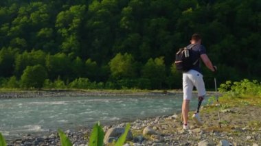 Engelli erkek gezgin dağ nehri kıyısında tek başına yürüyor.