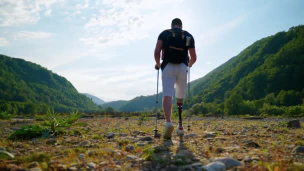 Чоловік мандрівник зі штучною ногою досліджує гори — стокове відео