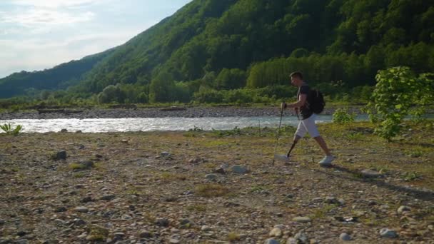 Protez bacaklı erkek turist yaz tatilinde doğa yürüyüşü yapıyor. — Stok video