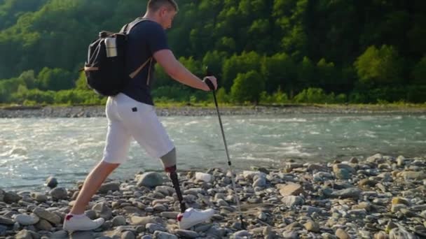 Пеший турист с протезной ногой преодолевает скалистую тропу — стоковое видео