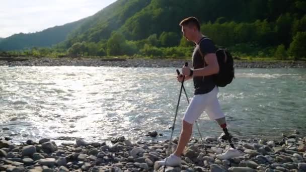 Excursionista discapacitado con la pierna protésica está paseando por la orilla del río en el parque natural — Vídeos de Stock