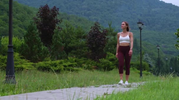 Female athlete having a break and walking in green park — Stockvideo