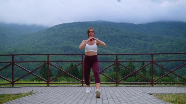 Woman athlete working out against mountain landscape — Video