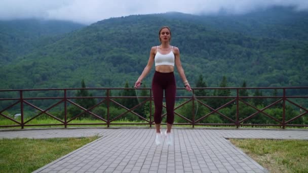 Energetic sporty woman is skipping rope during morning exercises outdoors — Video