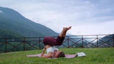 woman is performing yoga asana for training balance and strength in park