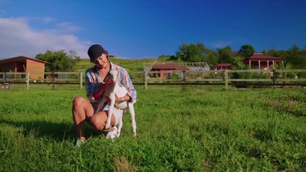 Granja orgánica en el área ecológica, mujer trabajadora está jugando con cabra bebé en el césped — Vídeo de stock