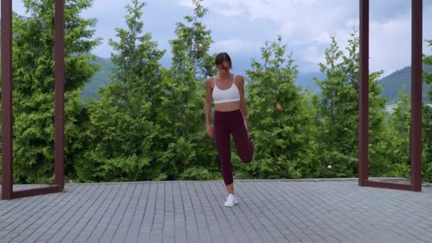 Athletic girl doing standing quad stretch on outdoor training — Stok video