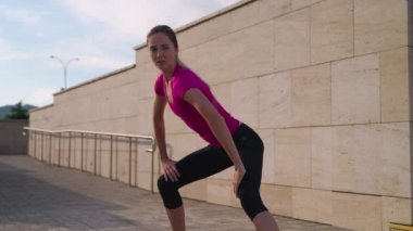 sportswoman is doing physical exercise outdoors in city in morning