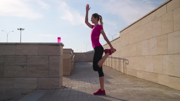 Ćwiczenia fizyczne dla równowagi, kobieta stoi na jednej nodze, trening w mieście rano na świeżym powietrzu — Wideo stockowe