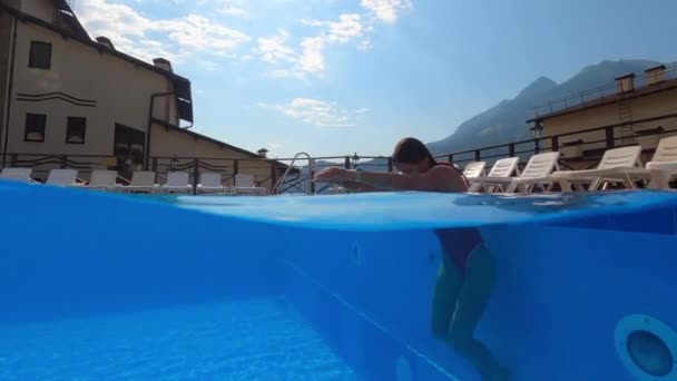 Sexy lady is swimming in outdoor pool of small hotel, plunging and floating underwater — Stock Video