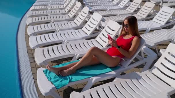 Jeune femme avec mobile relaxant au bord de la piscine — Video