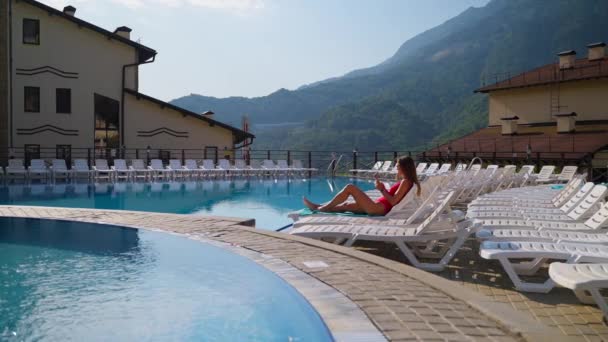 Montanha hotel exterior e mulher convidado relaxante à beira da piscina — Vídeo de Stock