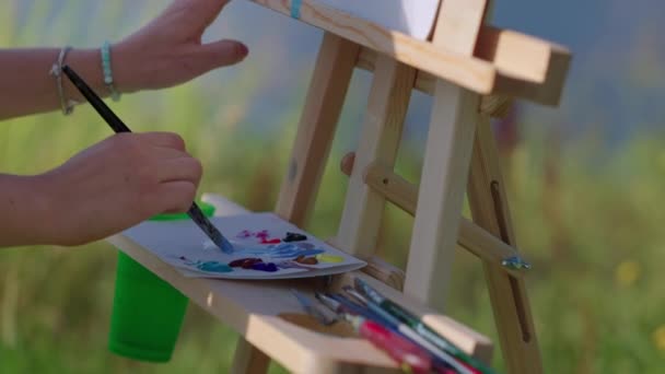 Женщина-художник рисует акриловыми красками на пленэре — стоковое видео