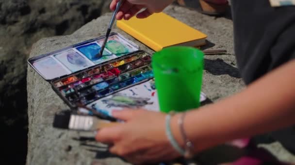 Malerin mischt bei der Arbeit Aquarellfarbe mit Wasser — Stockvideo