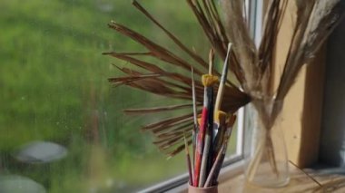 Sanat atölyesinde, pencere pervazında fırçalar.