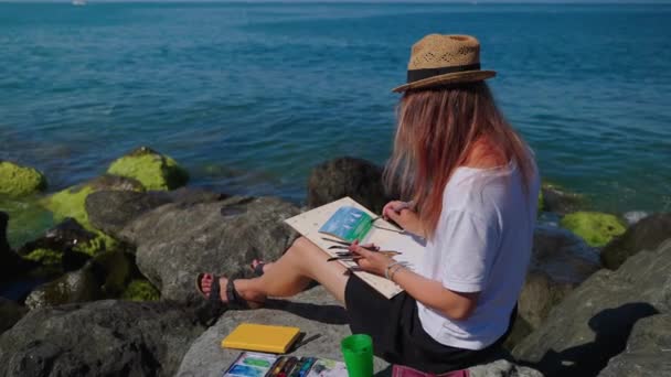 Ung kvinna vilar på stranden och måla Aquarelle marina landskap — Stockvideo