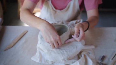 Çömlek atölyesinde çanak çömlek yapan bir kadın.