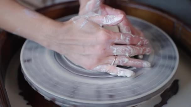 Woman is kneading clay on pottery wheel, preparing to make ceramic cup or vase — Stock Video