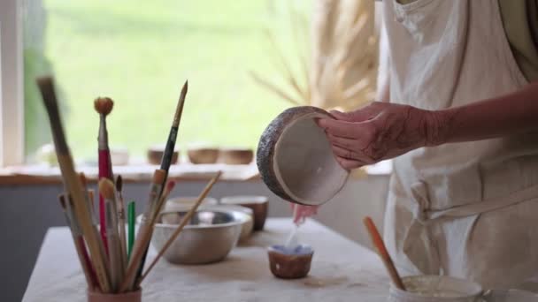 Mulher qualificada está pintando tigela de cerâmica na oficina artística — Vídeo de Stock