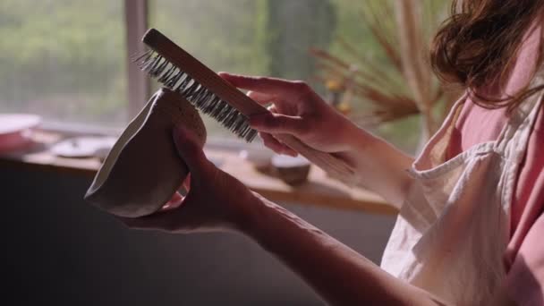 Ceramista usando escova áspera para fazer textura em tigela artesanal — Vídeo de Stock