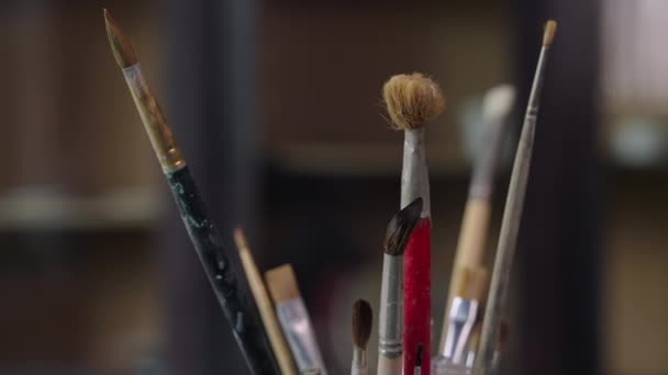 Dentro da oficina artística do pintor, suporte com escovas na mesa de trabalho — Vídeo de Stock