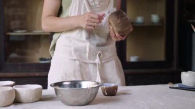Potter seramik kaseyi bitirmek için parlatıcı sürüyor