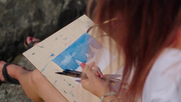 Женщина-художник рисует морской пейзаж под открытым небом — стоковое видео