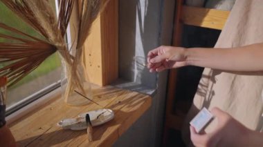 Kadın sanat atölyesinde tütsü yakıyor.