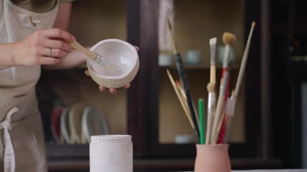 여성 도공은 작업장, 미술 및 창조적 취미로 도자기 그릇에 그림을 그리고 있다 — 비디오