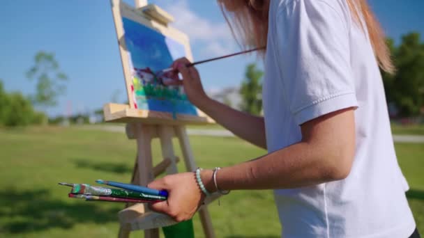 Vrouw oefent haar creatieve hobby schilderen in park in de zomer dag — Stockvideo