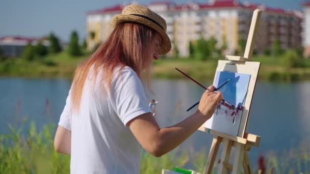 여자 가 공원에서 도시 경관을 그리고 있다. 예술가들 이 야외에서 작업을 시작하고 있다. — 비디오