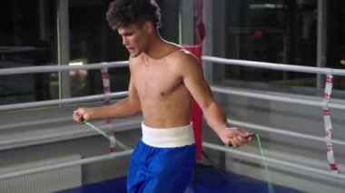Spor kulübünde antrenman yapan Afrikalı genç adam spor salonunda ip atlıyor, dayanıklılık ve güç kazanıyor, kaslar ve nefes alma egzersizleri yapıyor.