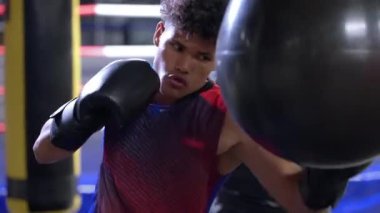 Yavaş çekim, antrenman sırasında konsantre olan İspanyol bir boksörün yumruk torbasına vurarak darbelerini vurmasını sağlar. Dövüş için hazırlanıyorum.
